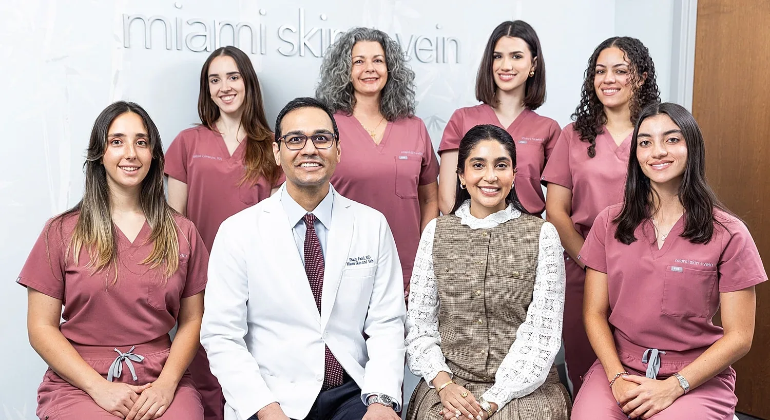 Eight team members posed beneath Miami Skin + Vein wall lettering.
