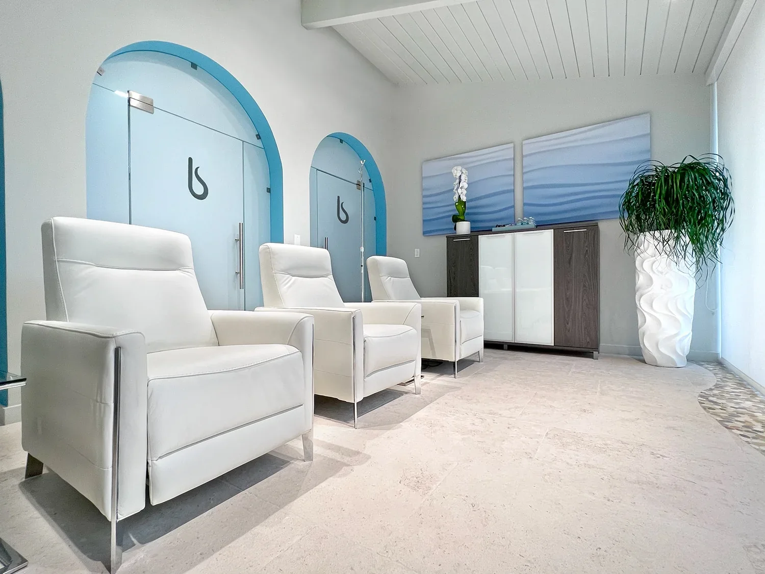 Empty lounge with white recliners and blue-trimmed doors at the biostation.