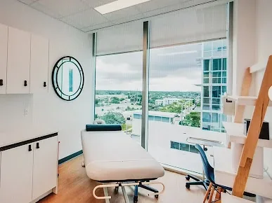 A white examination chair beside large windows in the Universal Medical & Wellness Center gallery.