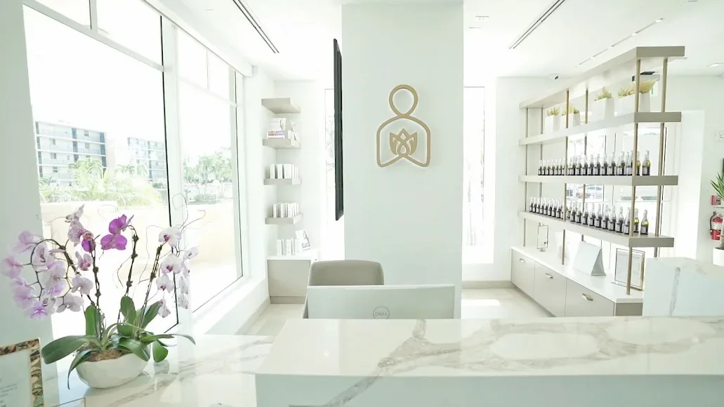 Empty marble-look reception counter with gold Beauty Within emblem and product shelves.