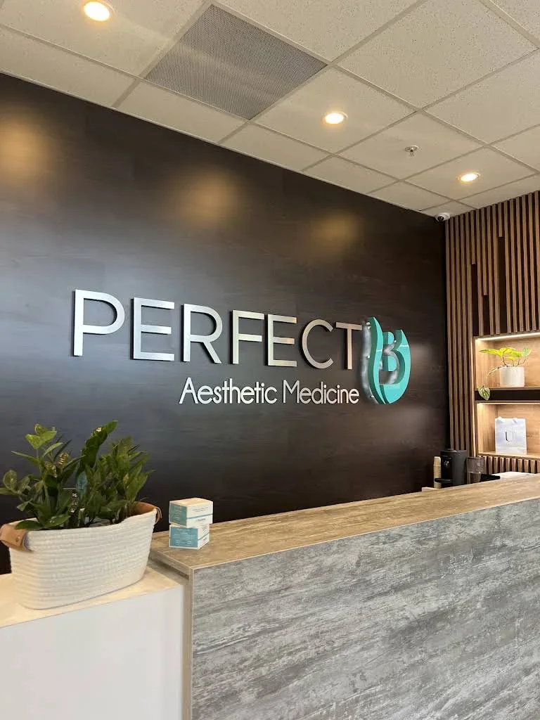 Empty reception counter and Perfect B wall sign with small plants.