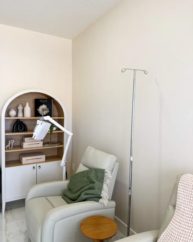 Empty room with white recliners, a green throw, an IV stand and display shelving.