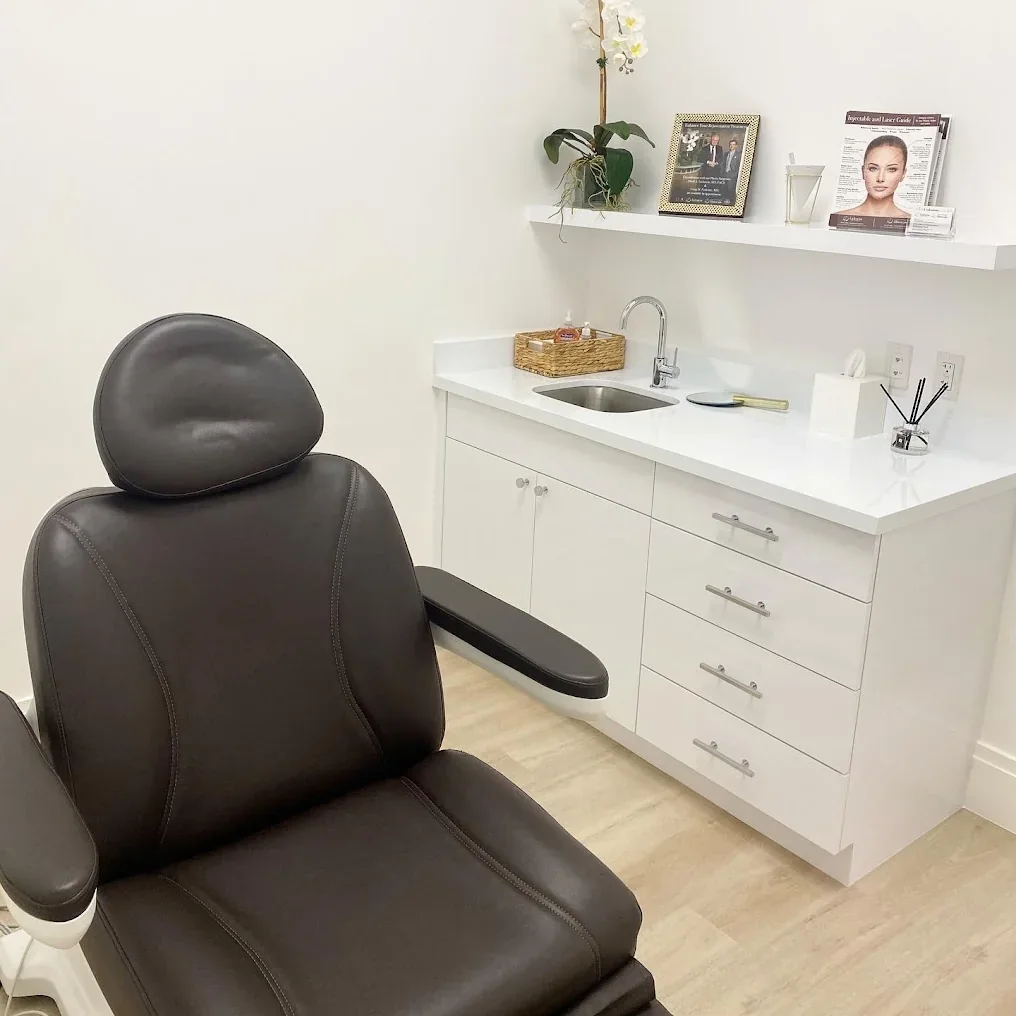Unoccupied room with dark reclining chair, white cabinets and a sink.