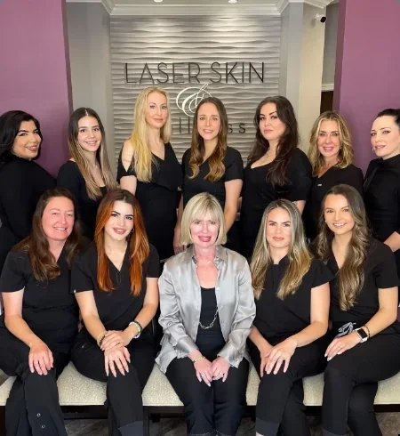 Laser Skin & Wellness staff posed together in front of the clinic logo.