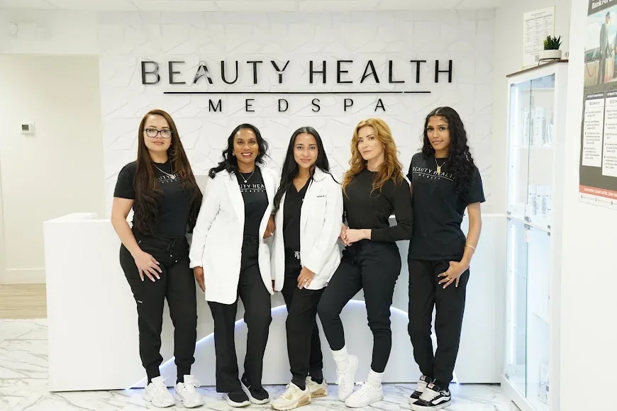 Five Beauty Health MedSpa team members posed in branded uniforms at reception.