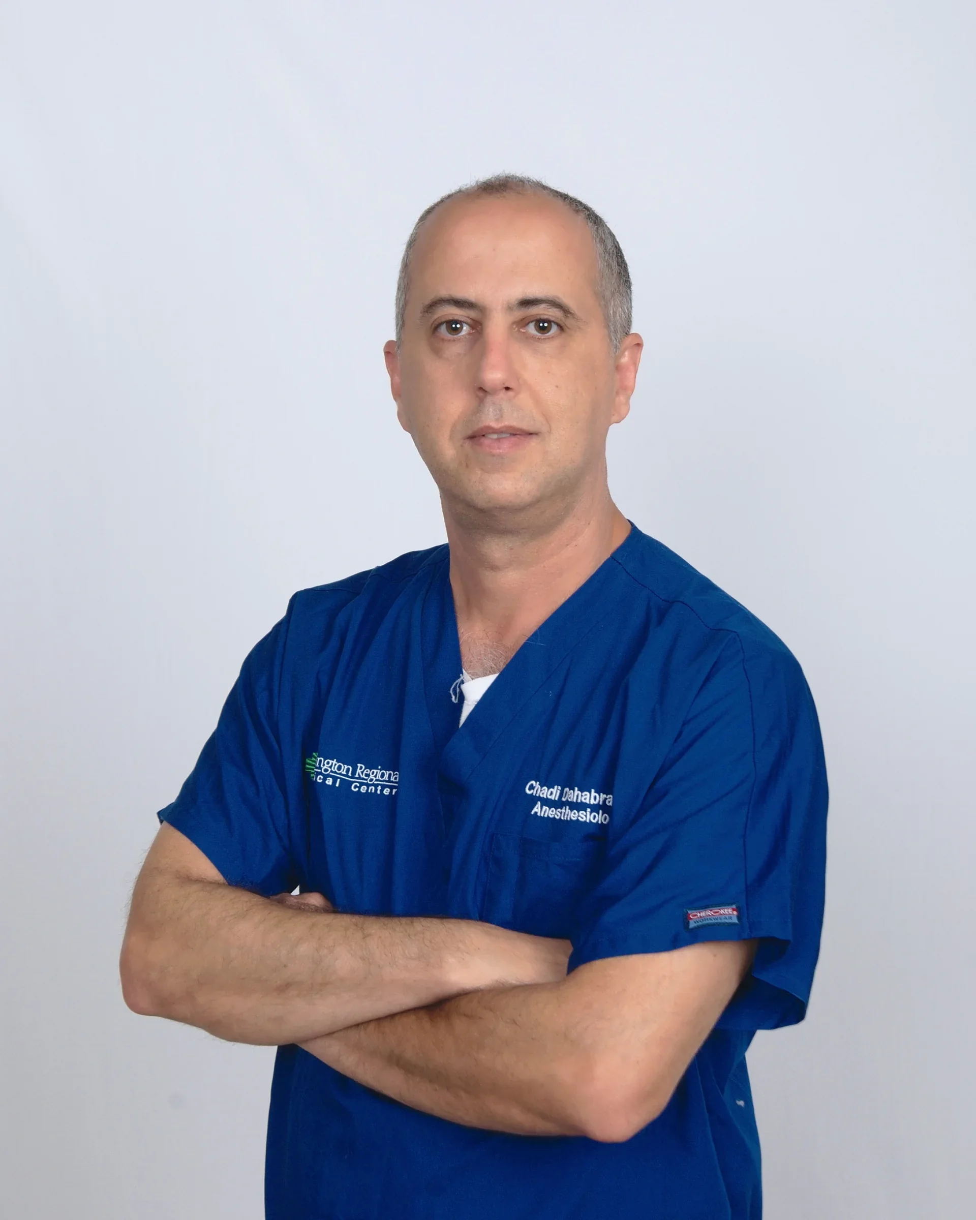 Professional portrait of Dr. Chadi Dahabra in blue scrubs.