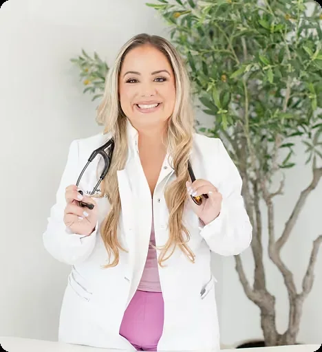 Stephanie Cabrera wearing a white coat and holding a stethoscope beside a plant.