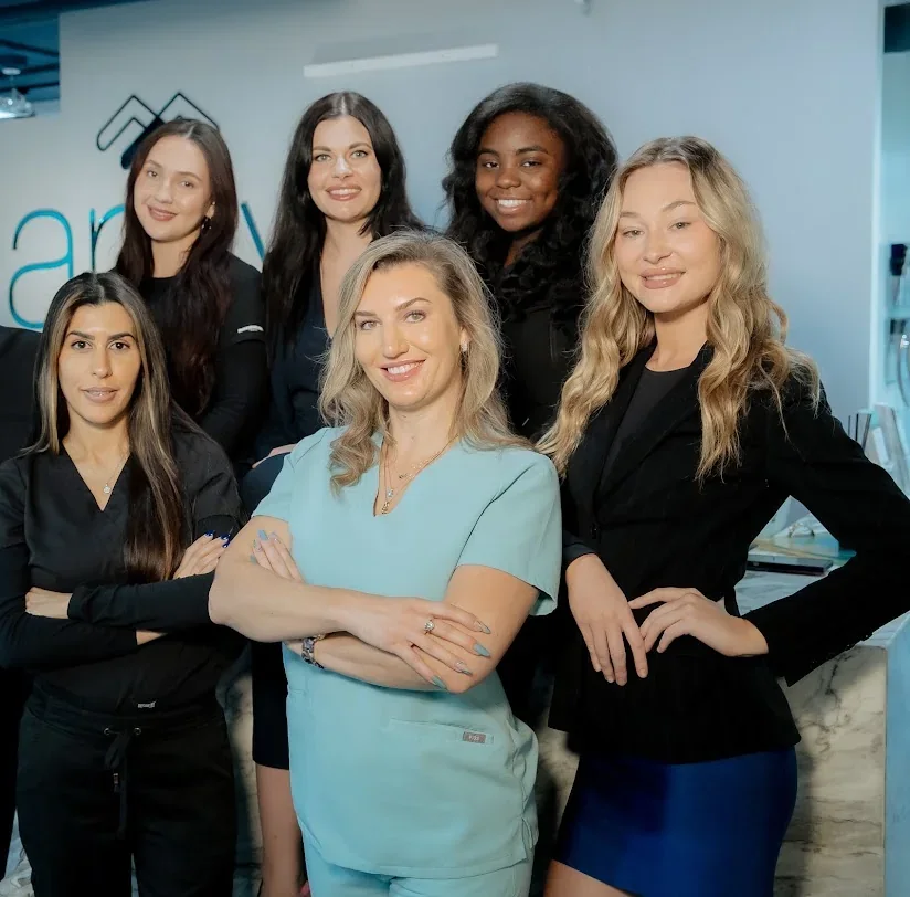 Arviv Miami team posed together in front of the branded reception wall.