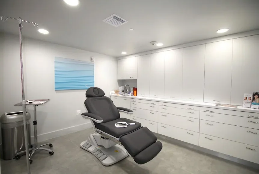 Empty private room with an adjustable chair, white cabinetry and blue wall art.