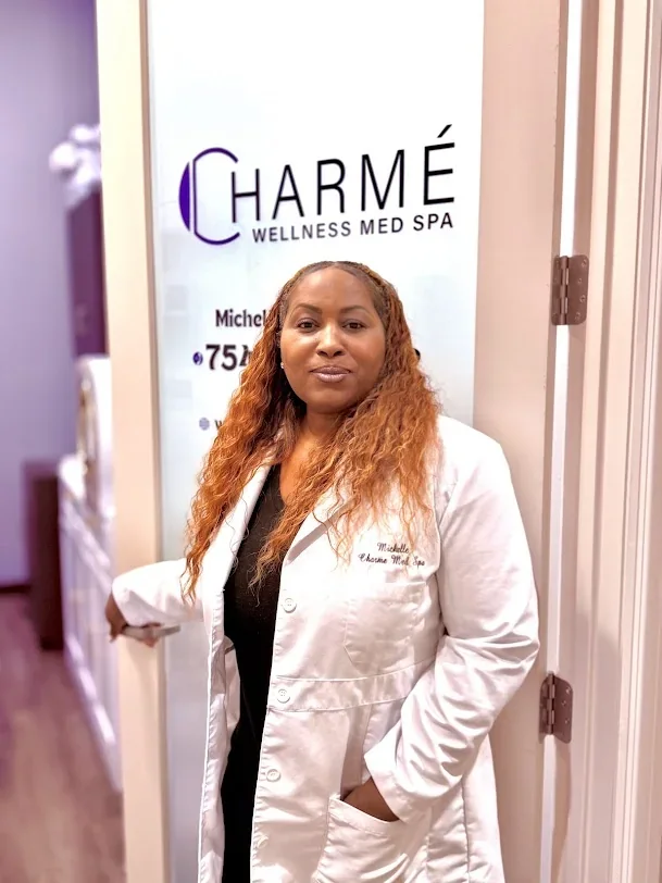 Practitioner in a white coat standing beside a Charme Wellness Med Spa glass door.
