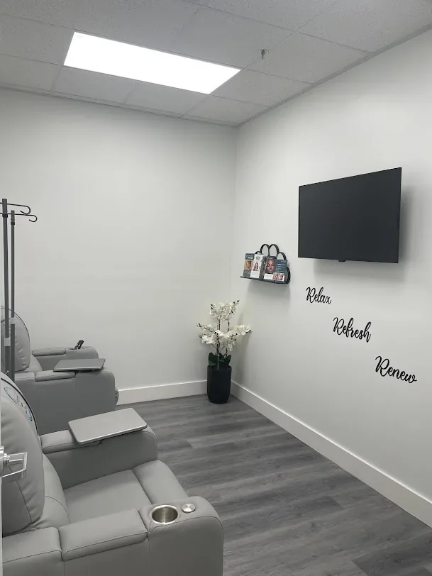 Empty room with gray reclining chairs, dark television and Relax Refresh Renew wall lettering.