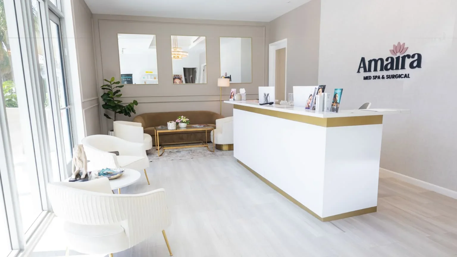 Amaira reception with white-and-gold desk and front-window seating.