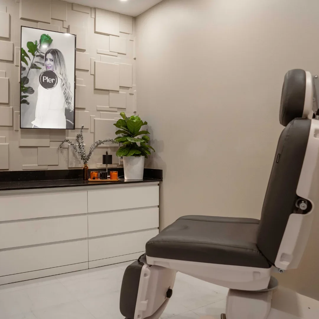 Empty gray chair beside white cabinetry, a plant and a Pler-branded wall display.
