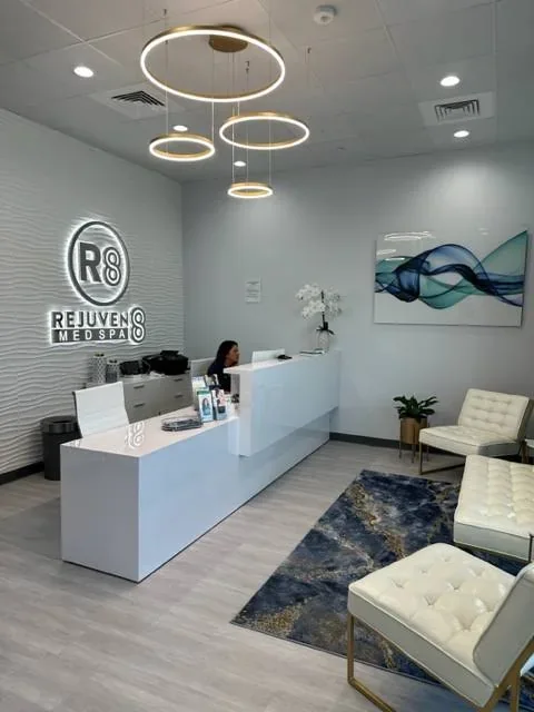 White reception counter, waiting chairs and Rejuven8 wall sign.
