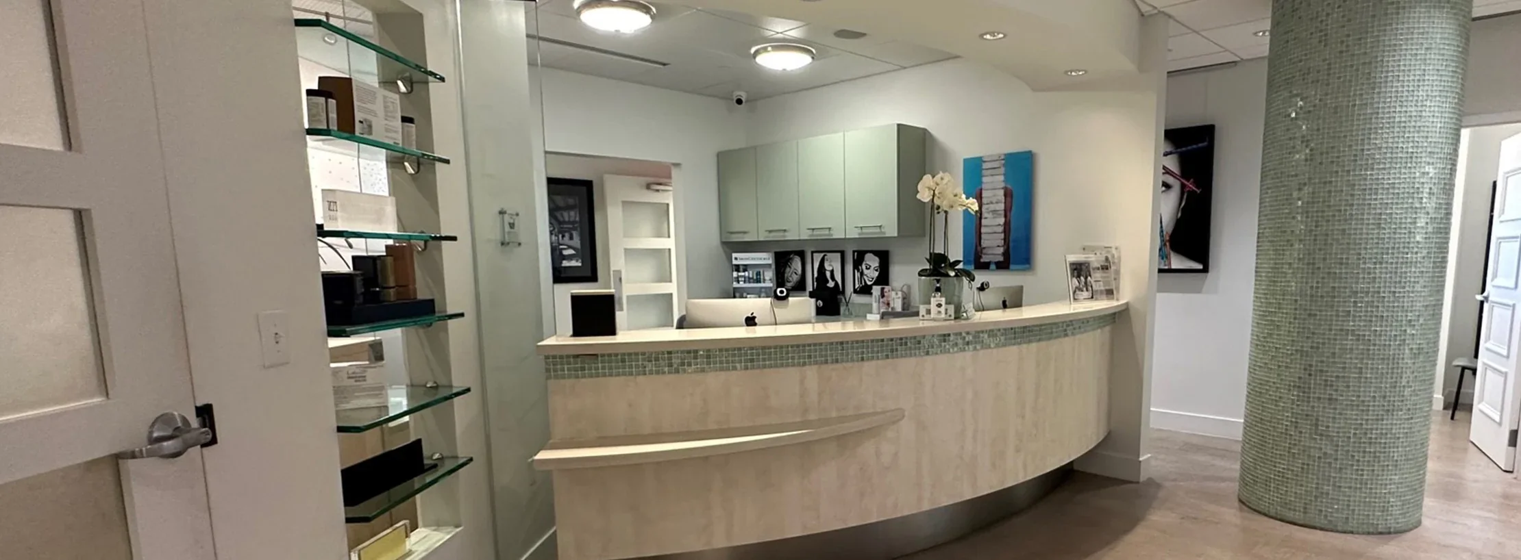 Empty reception counter with pale green mosaic tile, cabinets and product shelves.