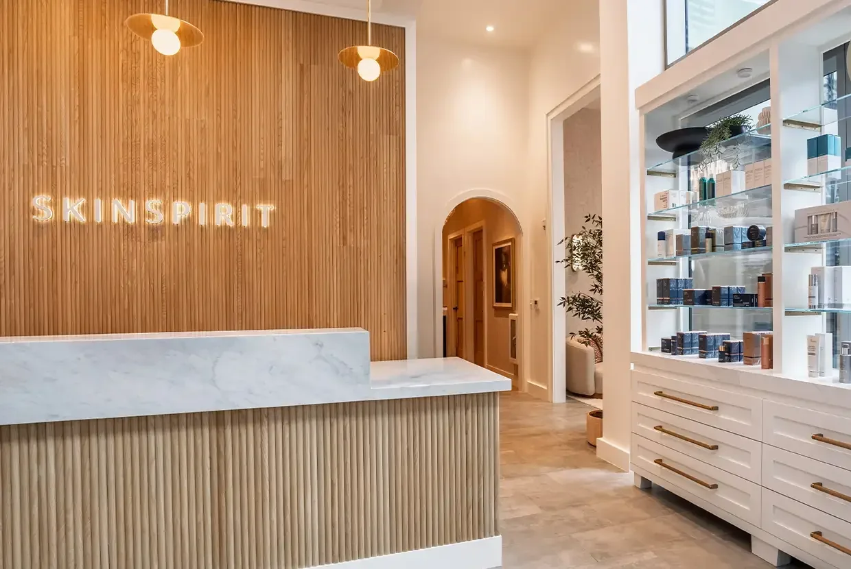 SkinSpirit wall sign, pale stone desk and glass product shelves.