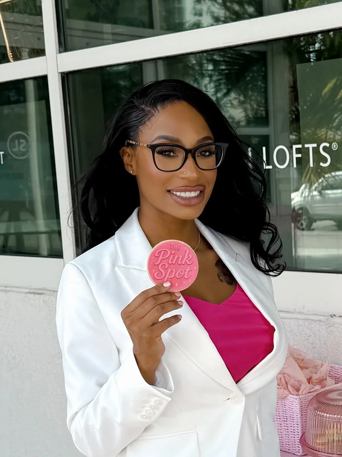 The Pink Spot owner holding a pink business-branded sign in a posed portrait.