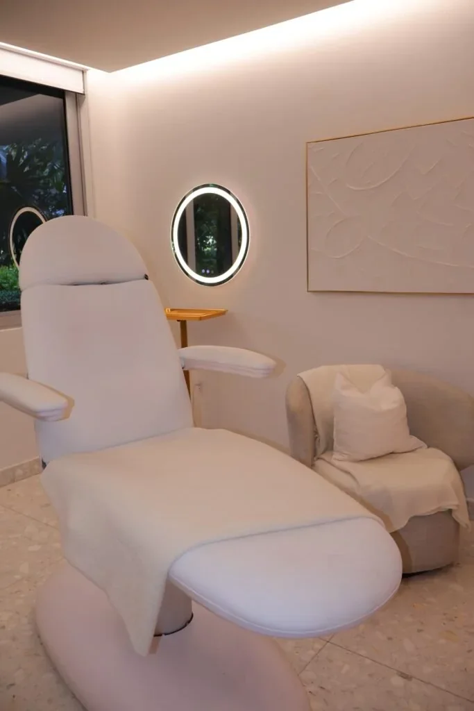 White treatment chair, side chair, ring light, wall art and a window.
