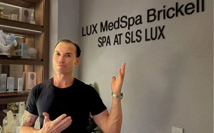 Alan Araujo beside LUX MedSpa Brickell's reception sign.