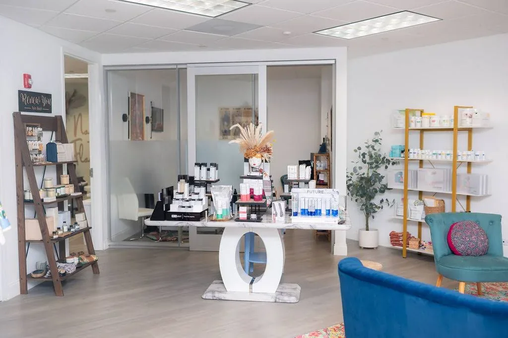 Skincare display table and shelves beside frosted office doors.