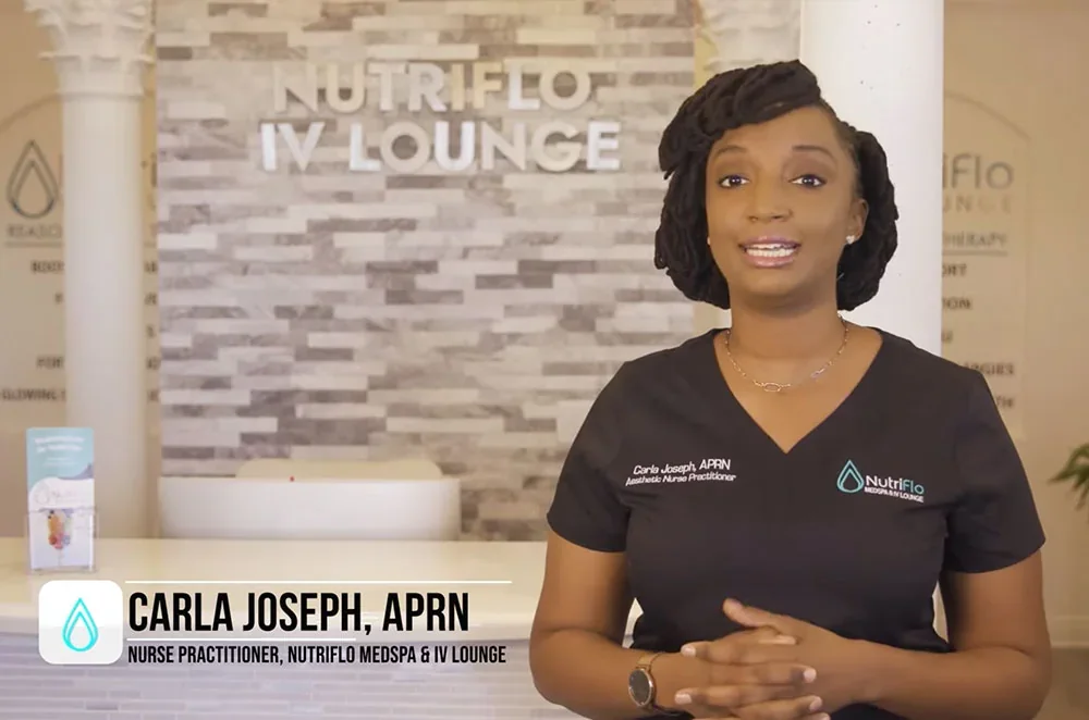 Carla Joseph in NutriFlo scrubs in front of the clinic's reception sign.