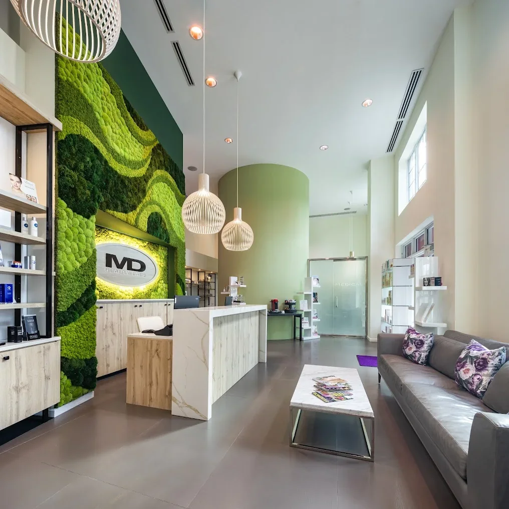 MD Beauty Labs reception with green moss feature wall, light wood desk and waiting sofa.