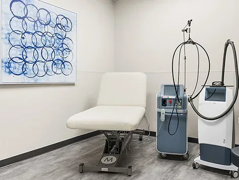 Empty cream chair beside inactive equipment and blue circular wall art.