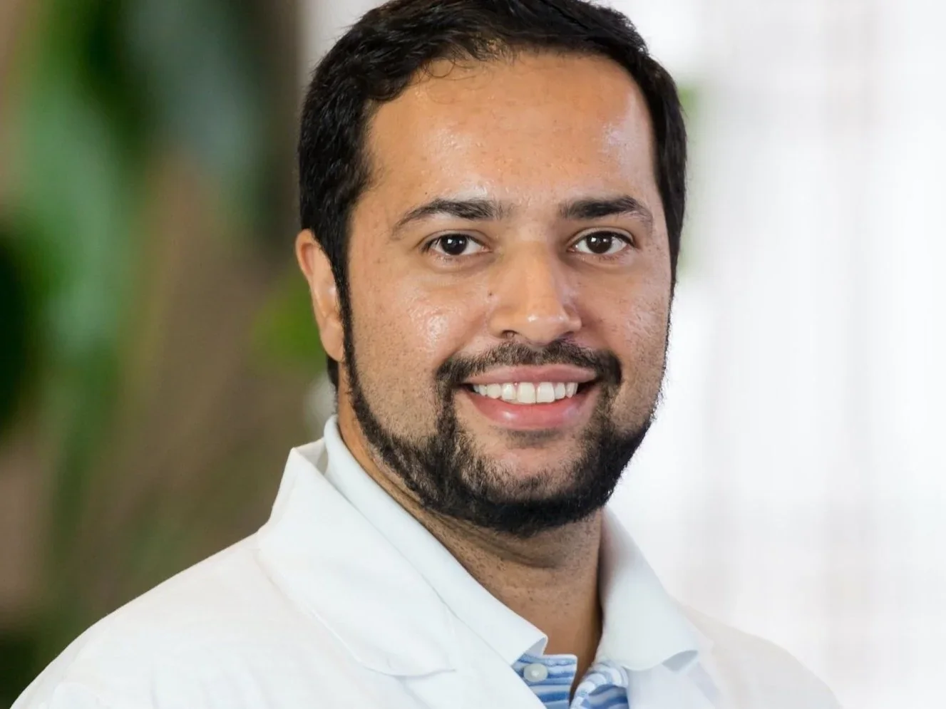 Portrait of Dr. Paldeep Atwal wearing a white coat against a softly blurred background