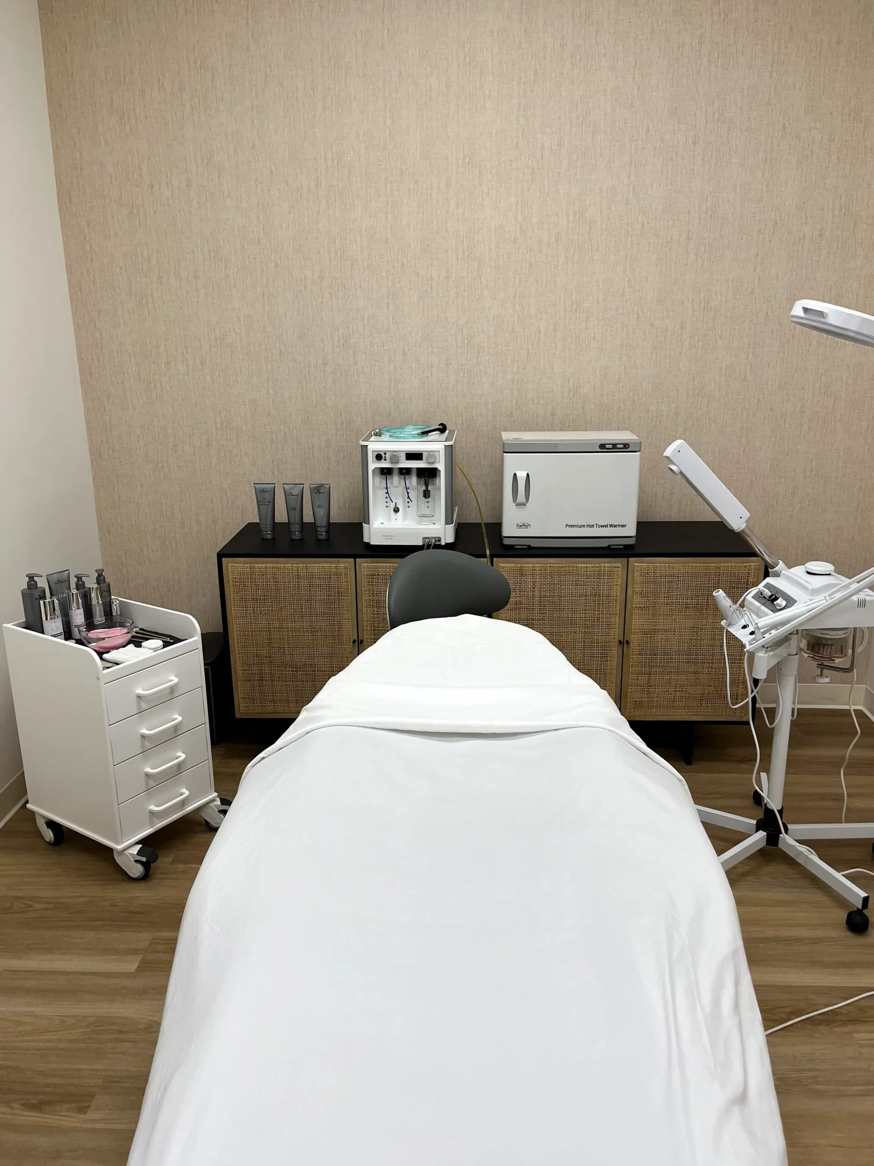 Empty treatment room with a white treatment bed and equipment at The Fountain.