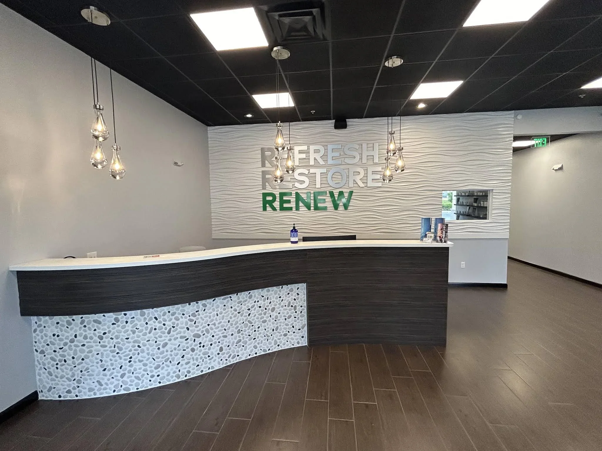 Empty angular reception counter beneath pendant lights and Refresh Restore Renew lettering.