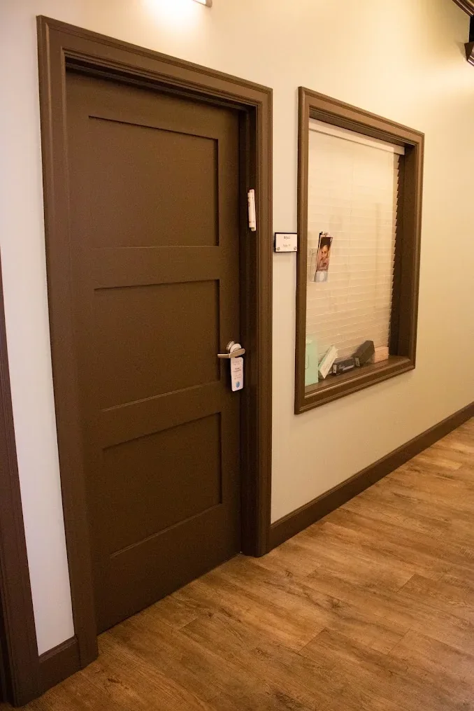 Brown suite door and interior window beside a RejuLi plaque in a shared corridor.