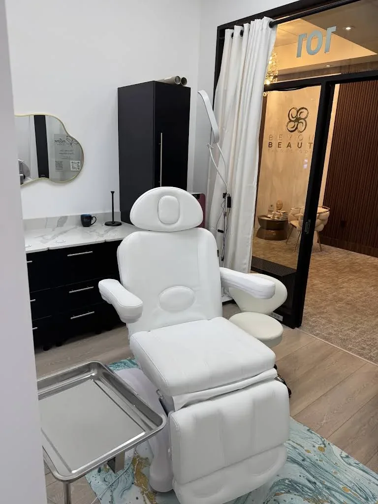 White reclining chair and dark cabinetry beside a Suite 101 glass doorway opening to the shared Beyond Beauty lobby.
