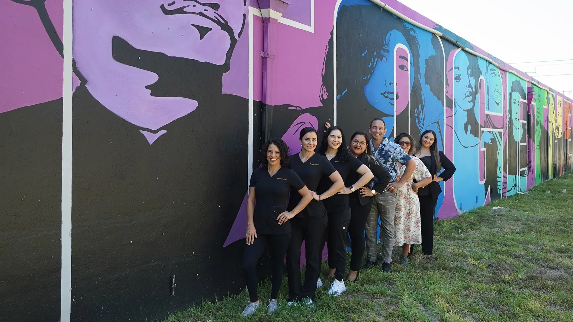 BeWell MedSpa team posed beside a colorful mural.