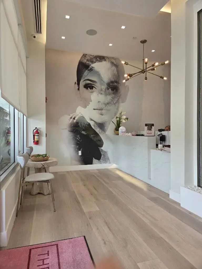 Reception desk, empty chairs and a large decorative portrait mural.