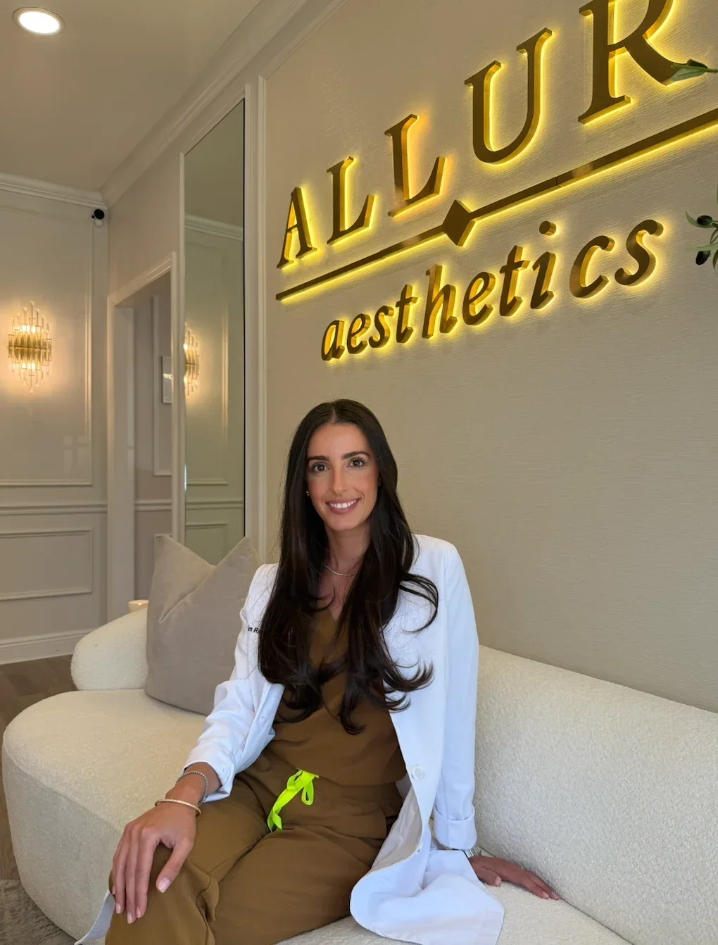 Allure Aesthetics clinician seated beneath the office sign