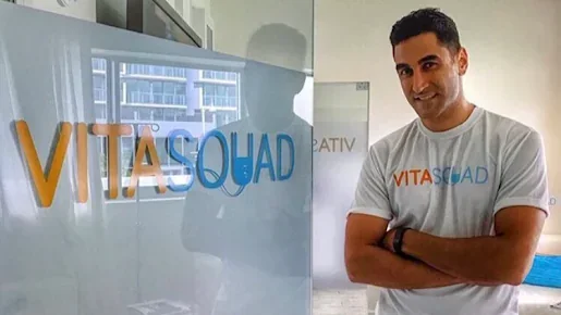 A VitaSquad team member beside the business's branded glass entrance.